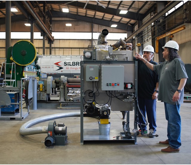 Two men standing and inspecting perlite expander equipment